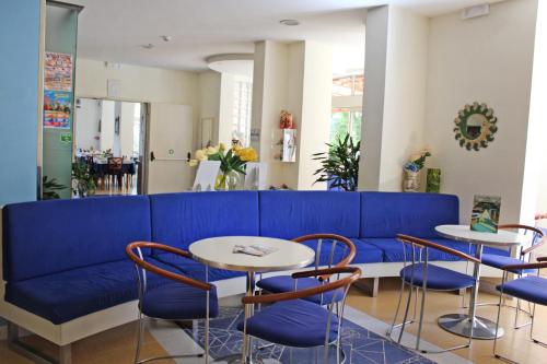 a blue couch in a room with tables and chairs at Hotel Metron in Cesenatico