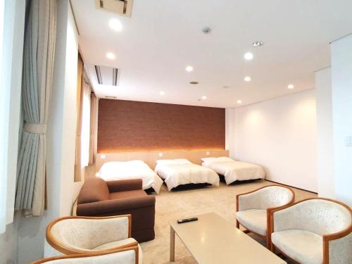 a hotel room with two beds and a table and chairs at KKRhakodate in Hakodate