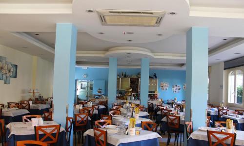 a dining room with tables and chairs and blue walls at Hotel Metron in Cesenatico