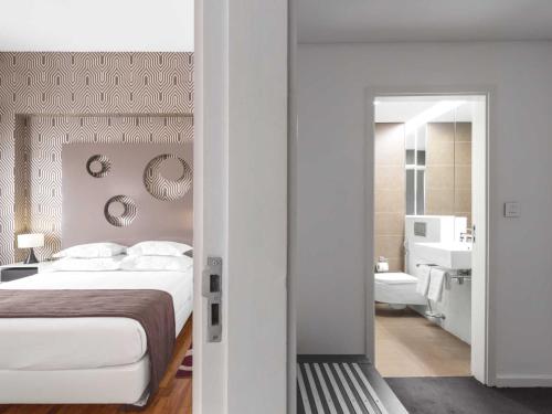 a bedroom with a bed and a bathroom at Hotel Tivoli Maputo in Maputo