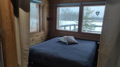 a small bedroom with a bed and two windows at Kaijonselän mökit Kaita in Kaitainen