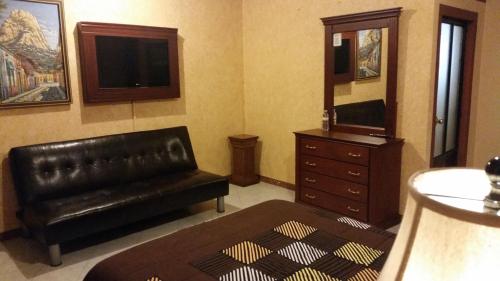 ein Wohnzimmer mit einem schwarzen Ledersofa und einer Kommode in der Unterkunft Hotel Villa Bernal in Bernal