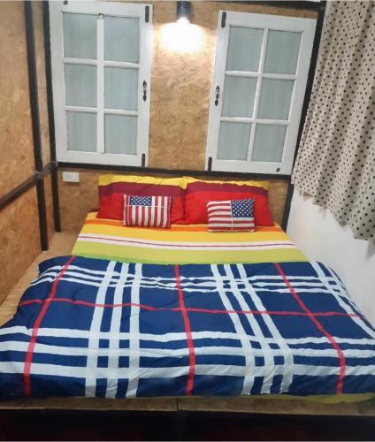 a bed with red white and blue sheets and two windows at Chiangmai by DD&B hostel in Chiang Mai