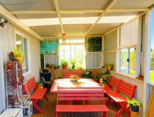 a porch with red benches and a table and chairs at The tiny homes at The Original Farm in Yass