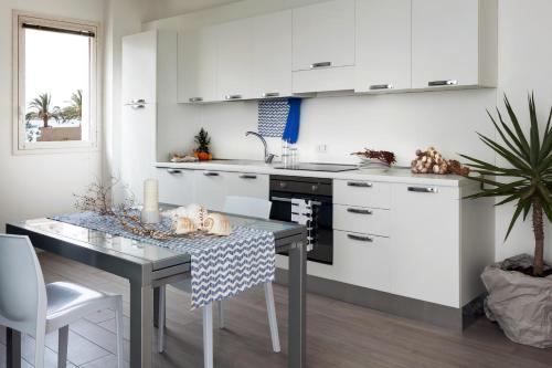 a kitchen with white cabinets and a dining table at Cala Palme Lampedusa in Lampedusa