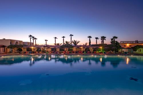 a large swimming pool with palm trees in the background at Eurovillage Achilleas Hotel in Mastichari