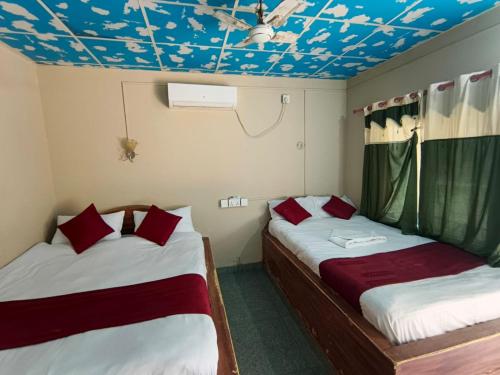 two beds in a room with a blue ceiling at Rapti Resort in Jhawāni
