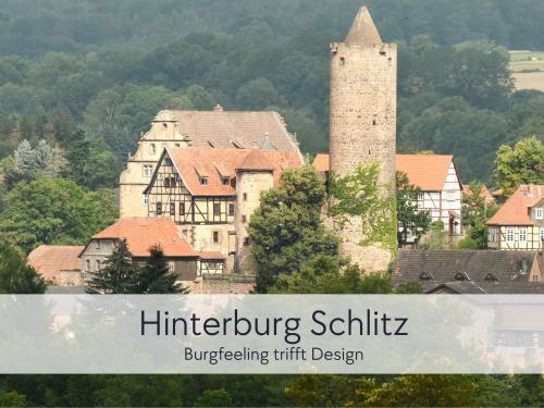 a building with a tall tower in a town at Amalias Burgwohnung - stilvolles Apartment mit Aufzug & Garten in der Hinterburg Schlitz - 2 Schlafzimmer, Parkplatz, Historisches Flair für Paare & Ruhesuchende in Schlitz