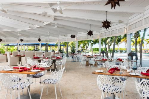 a dining area with tables and chairs and umbrellas at Blue Haven Resort- All Inclusive in Grace Bay