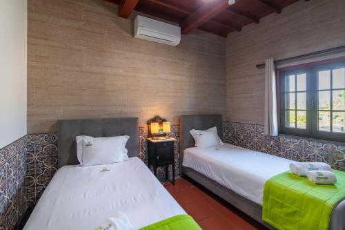 a bedroom with two beds and a table and a window at Heated Saltwater Pool-Private Beachside Oasis in Mosteiros