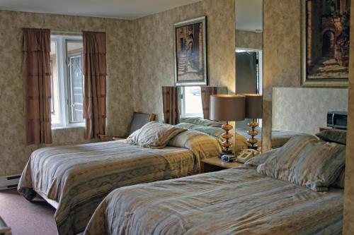 una habitación de hotel con 2 camas y una lámpara en Motel Bellevue, en Saint-Joseph-de-Beauce