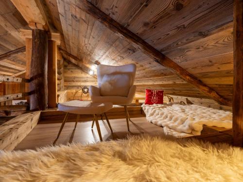 a room with a chair and a bed and a rug at Alpine Majestic Rascard - Unique Mountain Experience with Balcony and panoramic views in Champoluc