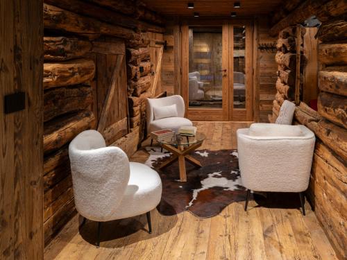 a log cabin living room with two chairs and a table at Alpine Majestic Rascard - Unique Mountain Experience with Balcony and panoramic views in Champoluc