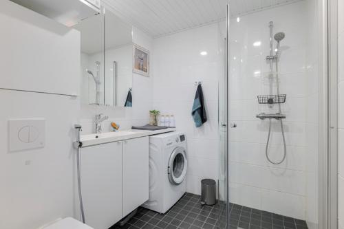a white bathroom with a washing machine and a shower at QnQ studio apartment in Helsinki