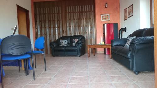 a living room with black leather furniture and blue chairs at B&B Verde Irpinia in Gesualdo