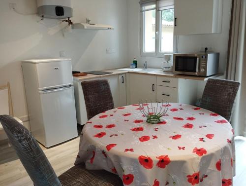 a kitchen with a table with red flowers on it at Entre Terre et Camargue- Studio de Charme in Le Cailar