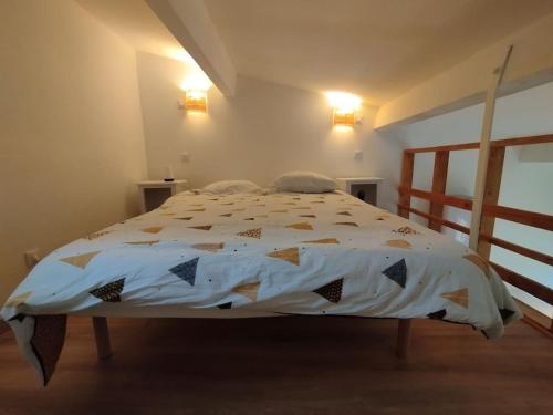 a bedroom with a bed with a comforter on it at Entre Terre et Camargue- Studio de Charme in Le Cailar