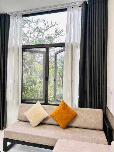 a couch with two pillows sitting in front of a window at MUN HOMESTAY in Hue