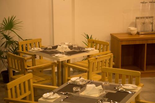 a dining room with a table and chairs with dishes on it at Kuredhi Beach Inn in Maafushi