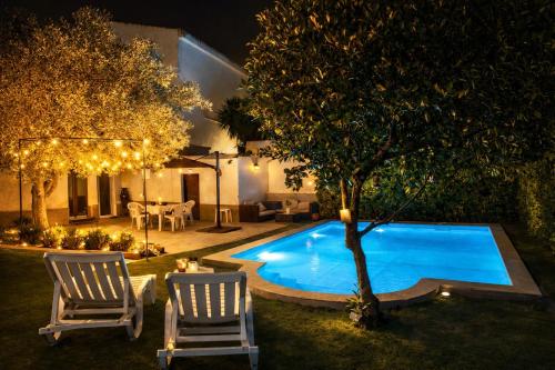 a backyard with a pool and two chairs and a tree at Casa Silva Diamond in Pinhal Novo