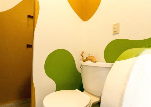 a bathroom with a toilet with a green and white wall at Red Pepper Popoyo in Popoyo