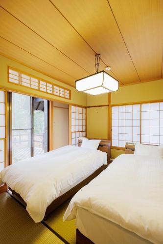 two beds in a room with yellow walls and windows at 山水苑-道-温泉付き貸別荘ガイアリゾート in Zao