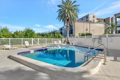 a swimming pool in a courtyard with chairs and a palm tree at Beach Access & Heated Pool Resort Condo for 8 in Clearwater Beach
