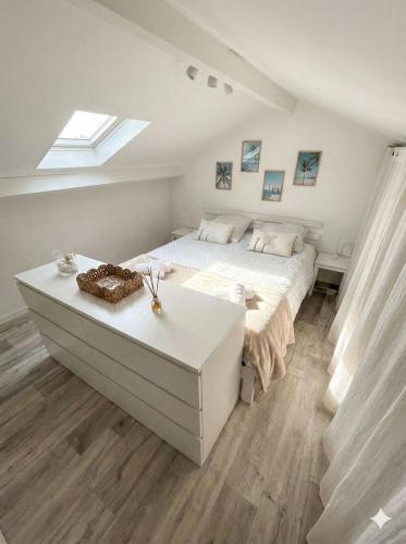a white bedroom with a bed and a table at Le Van T2 Spacieux 44m2 wifi Clim in Valras-Plage