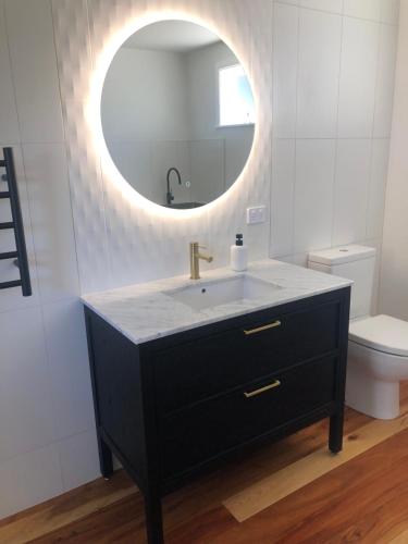 a bathroom with a sink and a mirror at Waihinau Cottage - One or Two Room Options! in Otaki