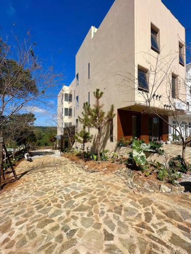a building with a stone walkway next to a building at Le VyN Mang Den in Kon Plong