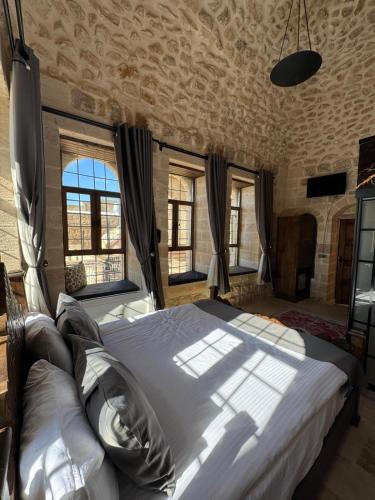 a bedroom with a large bed in a room with windows at Sıla Konağı Hotel in Mardin