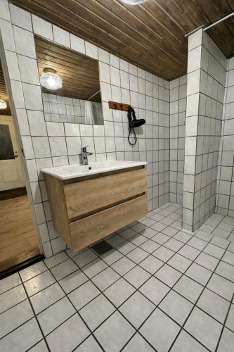 a bathroom with a sink and a tiled floor at Charmerende sommerhus i fredelige omgivelser in Skorping