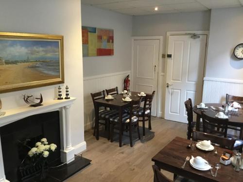 a dining room with a fireplace and a table and chairs at Cara Guesthouse in Whitley Bay