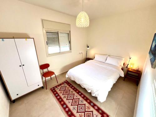 a bedroom with a white bed and a red rug at Cabin 168 in Neot Golan