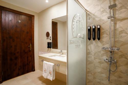 a bathroom with a sink and a shower with a mirror at The Old Village Hotel & Resort in Wadi Musa