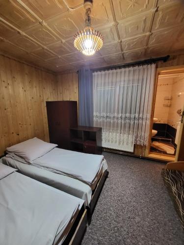 a bedroom with two beds and a chandelier at Agroturystyka Ela in Rzepiska