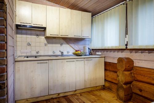 a kitchen with white cabinets and a bowl of fruit on the counter at Vila Ambasada in Šventoji