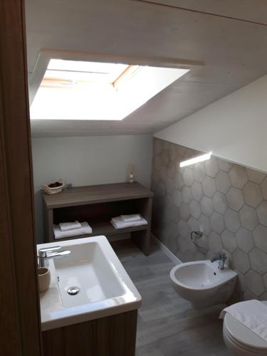 a bathroom with a sink and a toilet and a skylight at Ottocento Guest House in Alghero