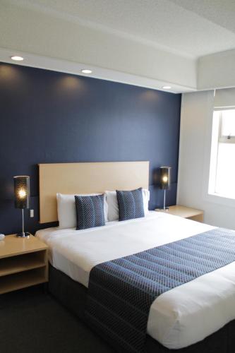 a bedroom with a large bed with a blue wall at Willis Wellington Hotel in Wellington