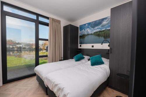 a bedroom with a large bed with a large window at Villa Nautica | 4 Pers. in Loosdrecht