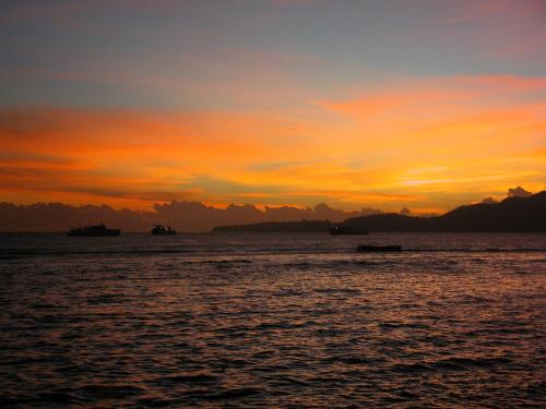 a sunset over the ocean with boats in the water at Oceanfront Citakara Sari Villas in Candidasa