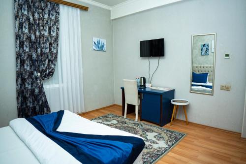 a bedroom with a bed and a desk with a television at Nemi Boutique Hotel in Baku