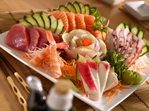 a plate of sushi and vegetables on a table at Vitória Hotel Concept Campinas in Campinas