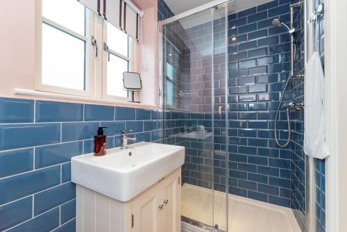 a blue tiled bathroom with a sink and a shower at The Station at Shustoke - Birmingham Airport & NEC in Shustoke