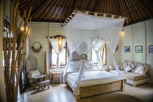 a bedroom with a canopy bed and a couch at Mondo Surf Village in Canggu