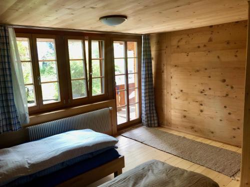 ein Schlafzimmer mit Holzwänden und -fenstern und einem Bett in der Unterkunft Chalet Ried Naturpark Diemtigtal in Diemtigen