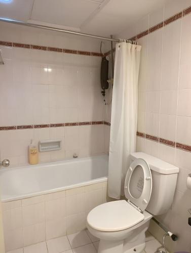 a bathroom with a toilet and a tub with a shower curtain at 2BR Seaview Condo with Balcony at Riviera Bay Resort, Melaka in Malacca