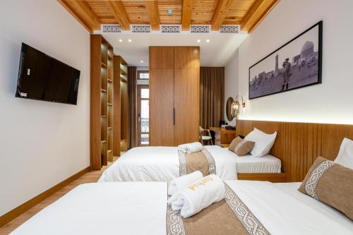 a hotel room with two beds and a flat screen tv at Hotel Sarhad Bukhara in Bukhara