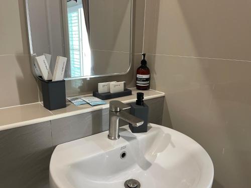 a bathroom sink with a mirror and a bottle of soap at Khwanlom House in Lampang