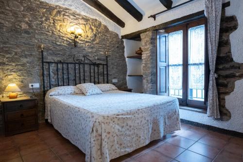 a bedroom with a bed and a stone wall at Apartaments Can Lo in Rupit